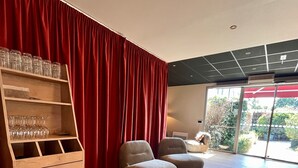 Ein modernes Wohnzimmer mit einem Holzschrank, zwei grauen Sesseln und einem roten Vorhang.