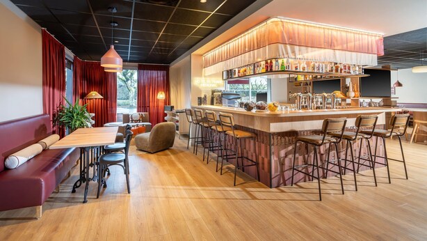Eine Bar mit Theke, Hockstühlen und einer Neonreklame.