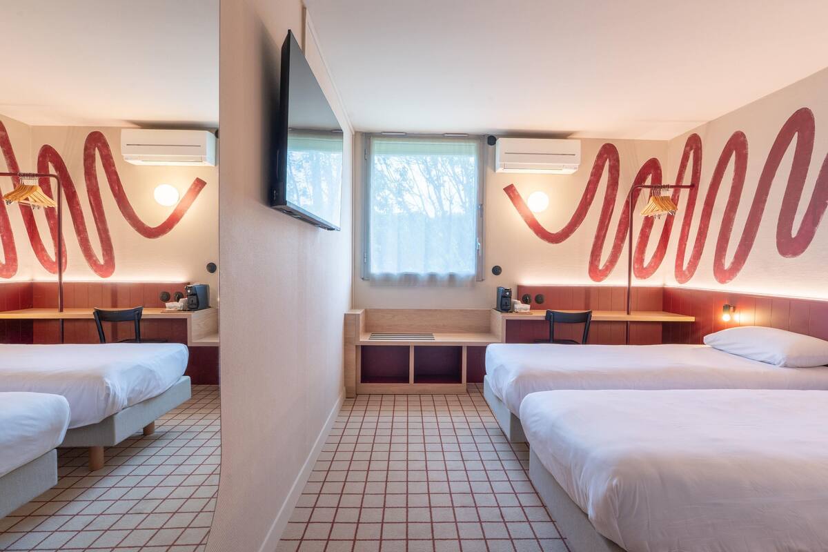 Ein Hotelzimmer mit zwei Betten, einem Schreibtisch und einem Fernseher.