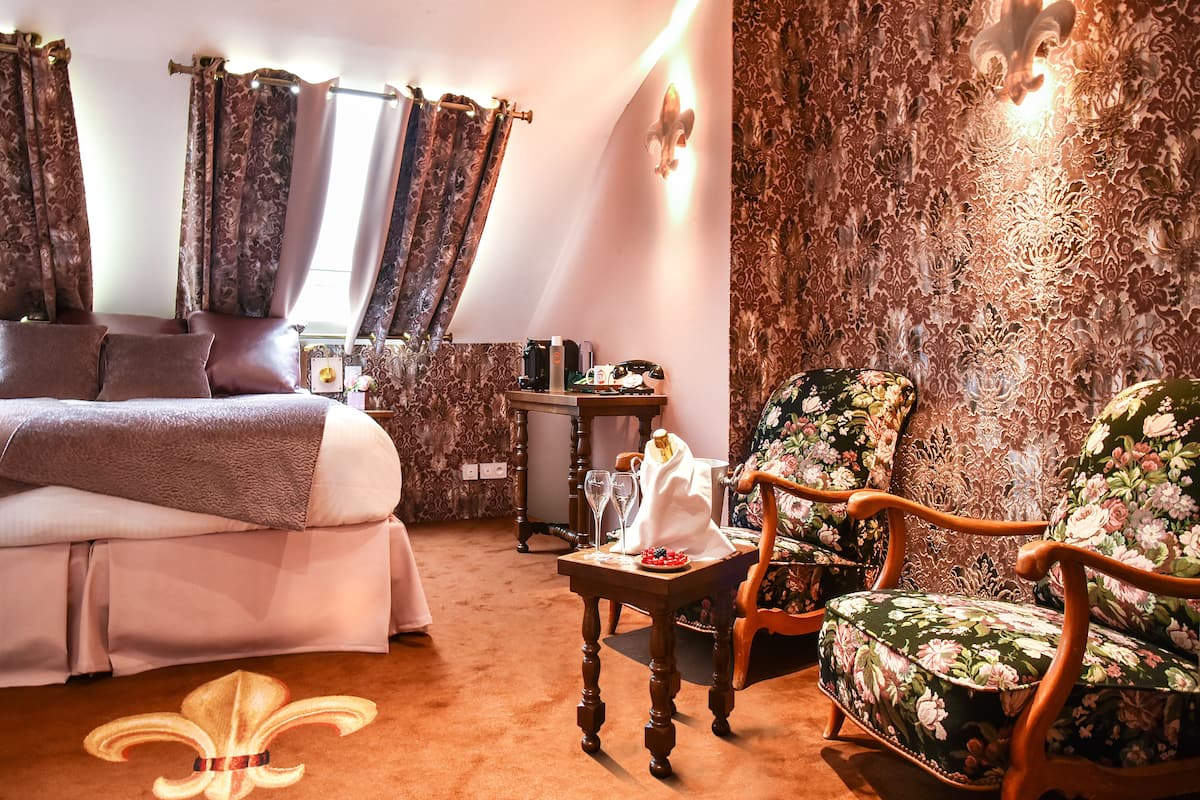Une chambre à coucher avec un lit, une chaise, une petite table et des rideaux.