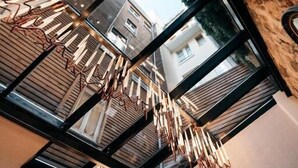 Un interior moderno con techo alto, ventanas amplias y un candelabro único.