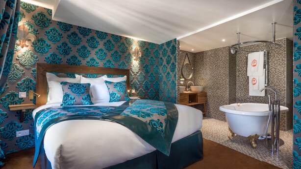 Un dormitorio moderno con una cama grande, un tocador con espejo y una bañera.