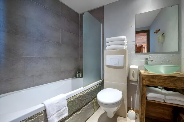 A modern bathroom with a bathtub, toilet, and sink.