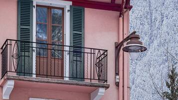 A two-story building with a balcony and a window with shutters.