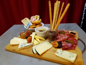 Une planche de charcuterie comprenant divers fromages, viandes, cornichons et biscuits salés.