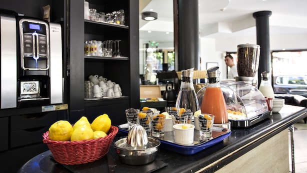 A breakfast buffet with various food items, a coffee machine, and a selection of glasses on a counter. - Occitania Centre Toulouse Matabiau (Toulouse)
