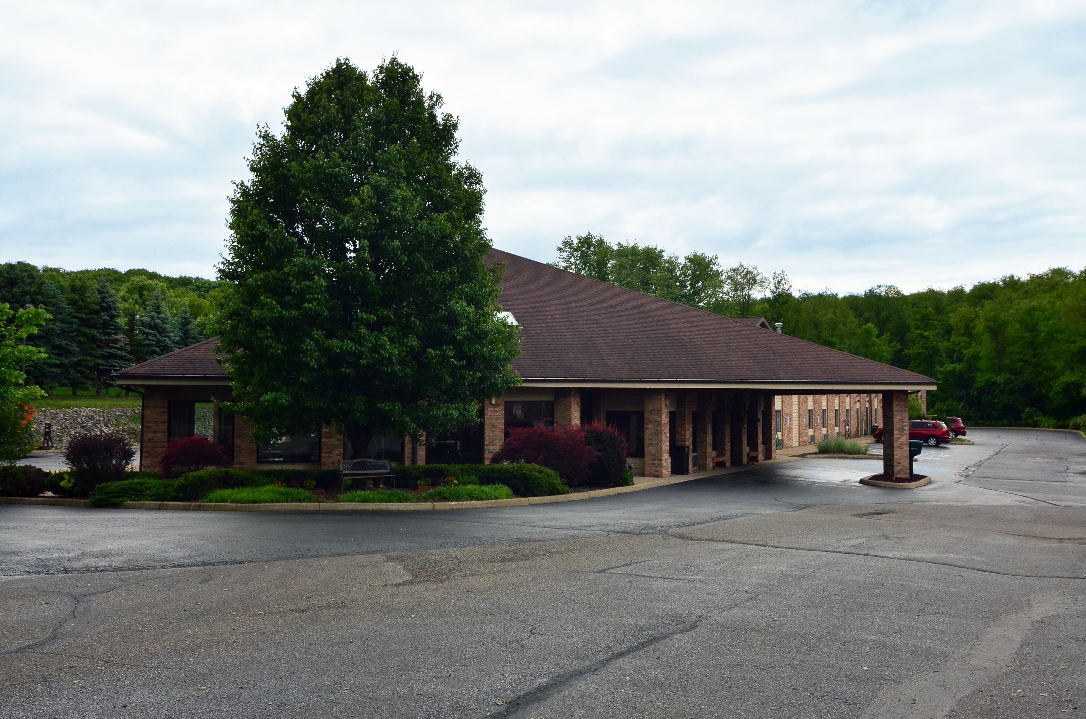 A building with a covered porch, brick exterior, and a parking lot.