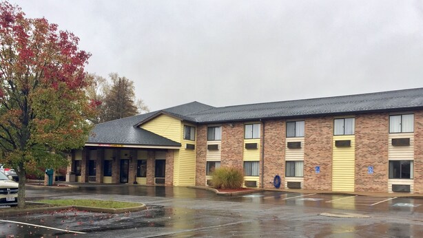 A multi-story hotel with a brick facade and yellow accents, featuring a covered entrance and a parking lot.