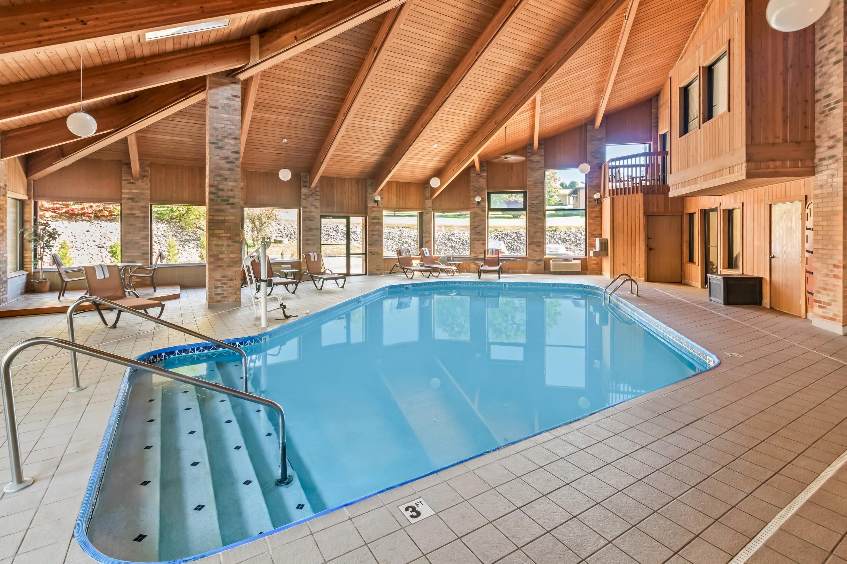 An indoor swimming pool with a wooden ceiling and large windows.