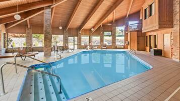 An indoor swimming pool with a wooden ceiling and large windows.