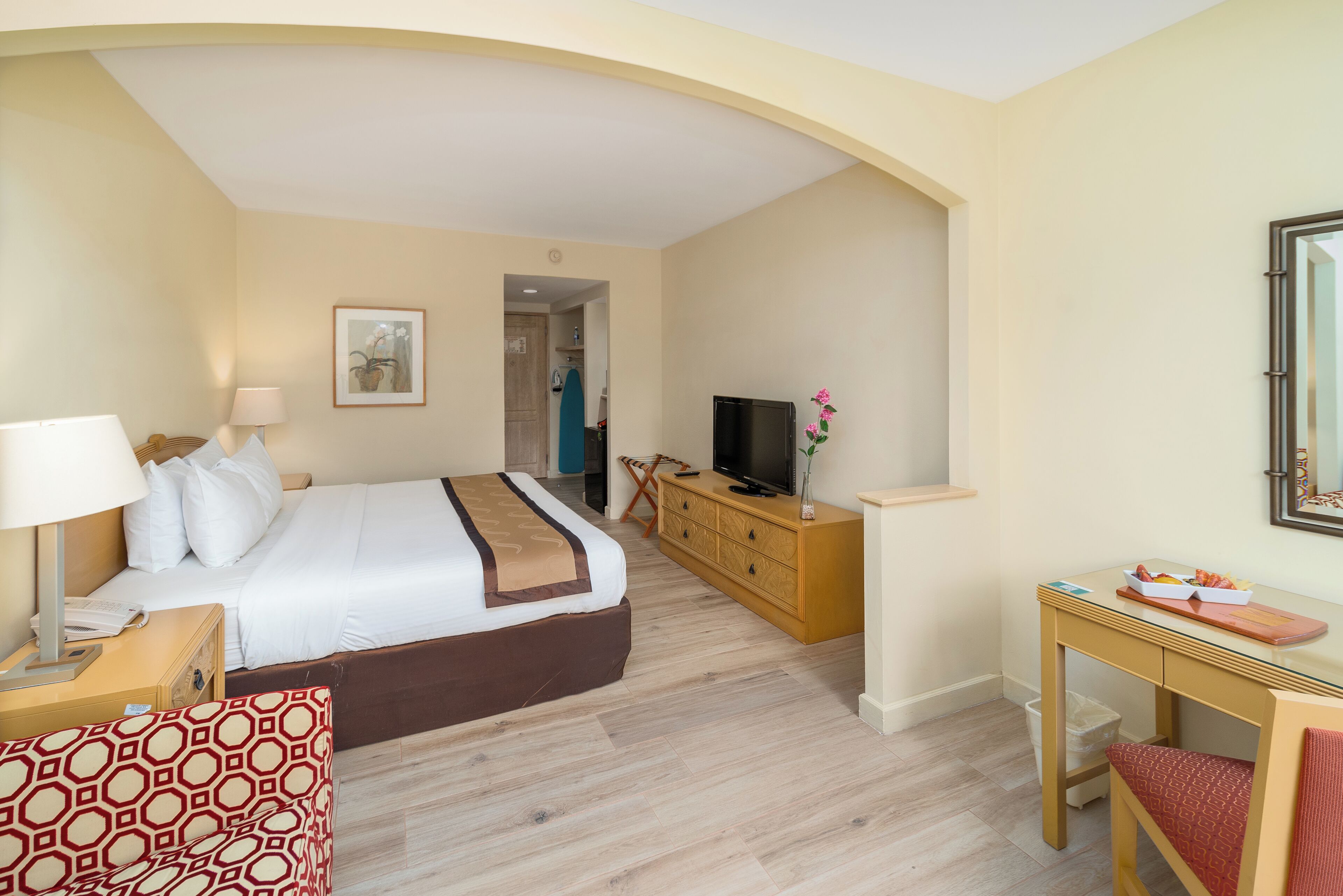 Een hotelkamer met een bed, een televisie, een bureau en een stoel.