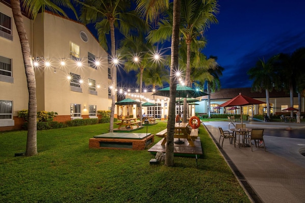 A well-lit outdoor area with picnic tables, umbrellas, and string lights. - Quality Hotel Real Aeropuerto (San Luis Talpa)