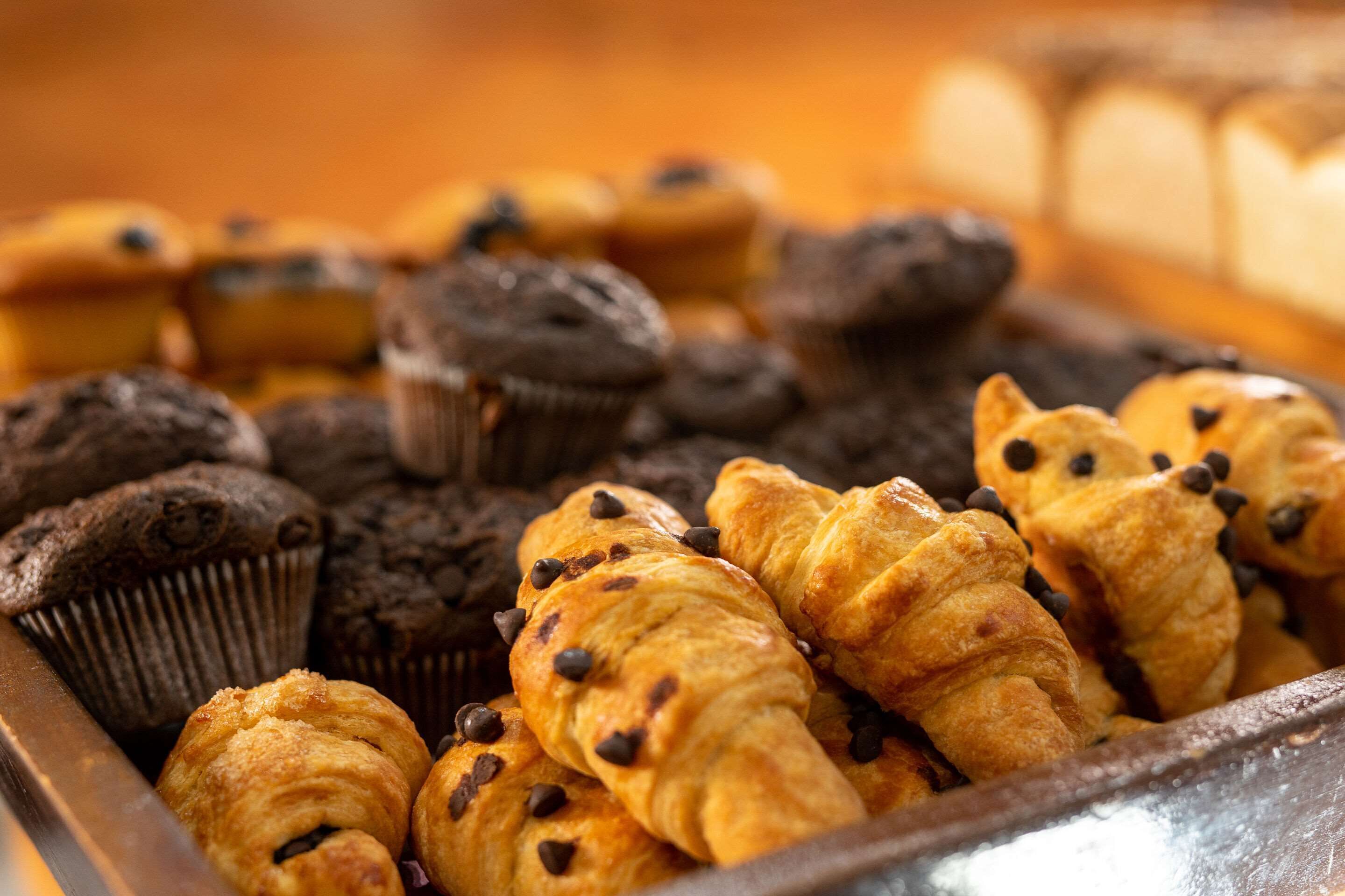 A tray of assorted baked goods including muffins and croissants.