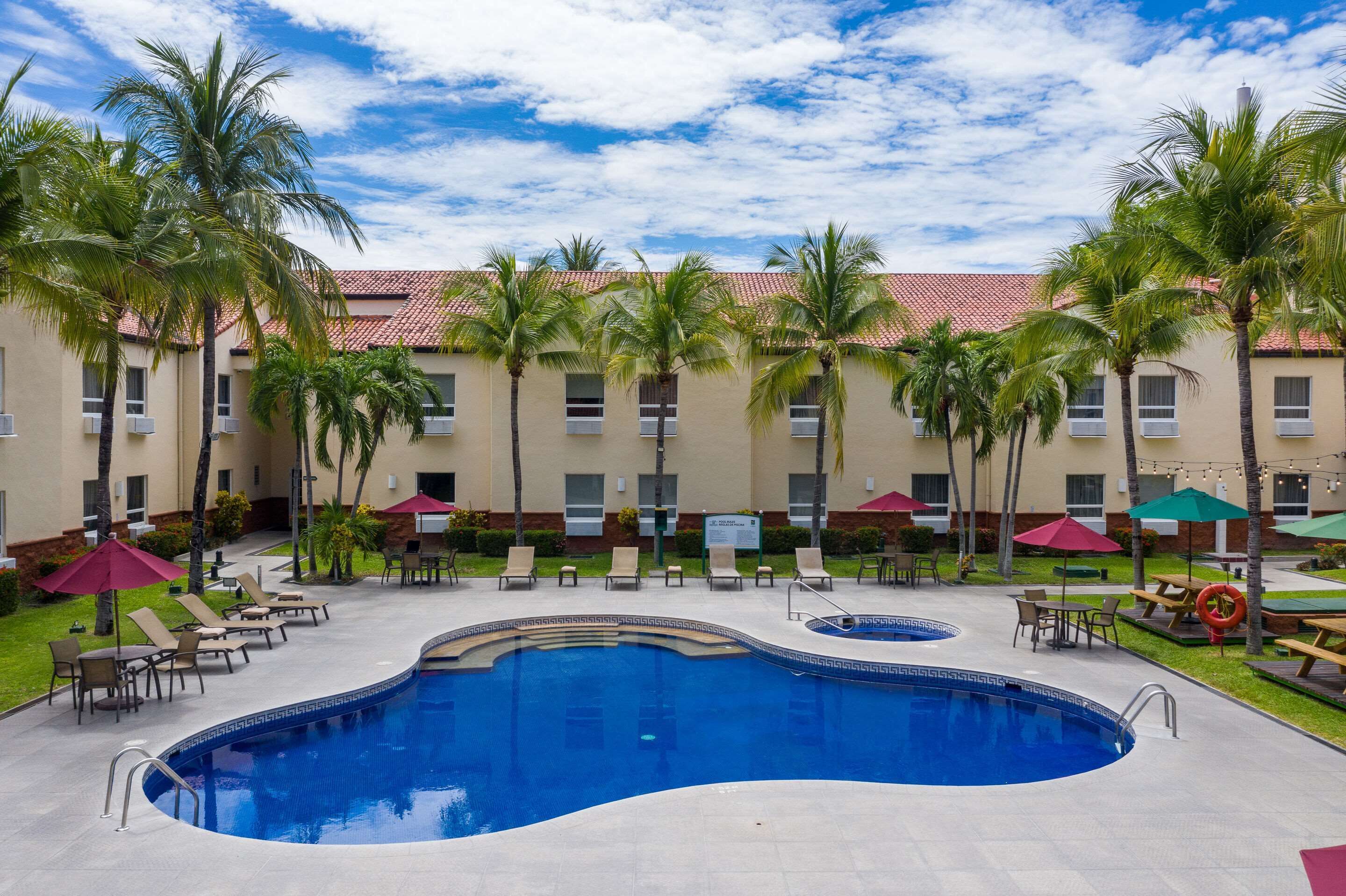 Een buitenzwembad, parasols bij het zwembad en ligstoelen