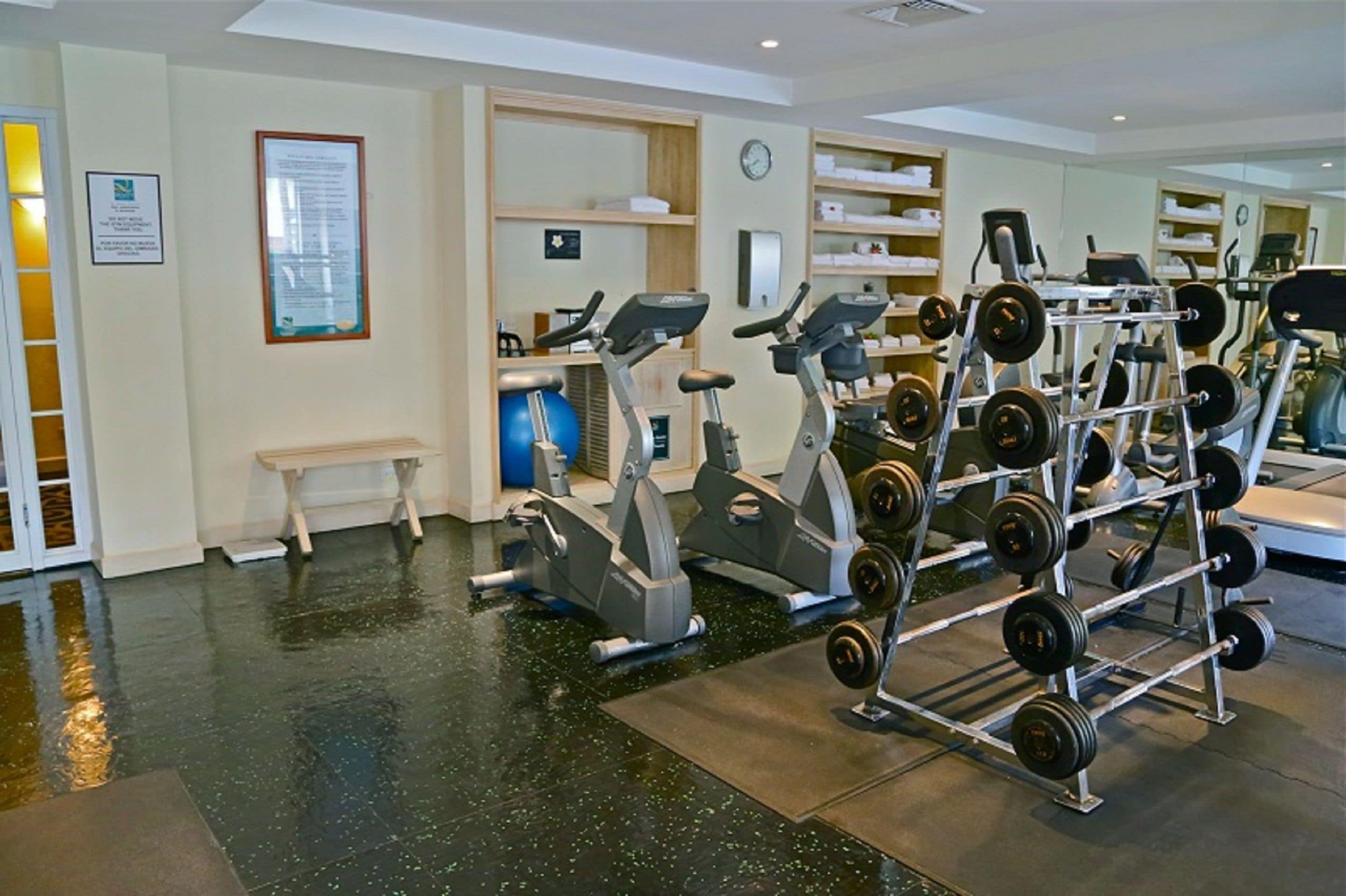 Un gimnasio con equipo de ejercicio, un reloj y un banco.
