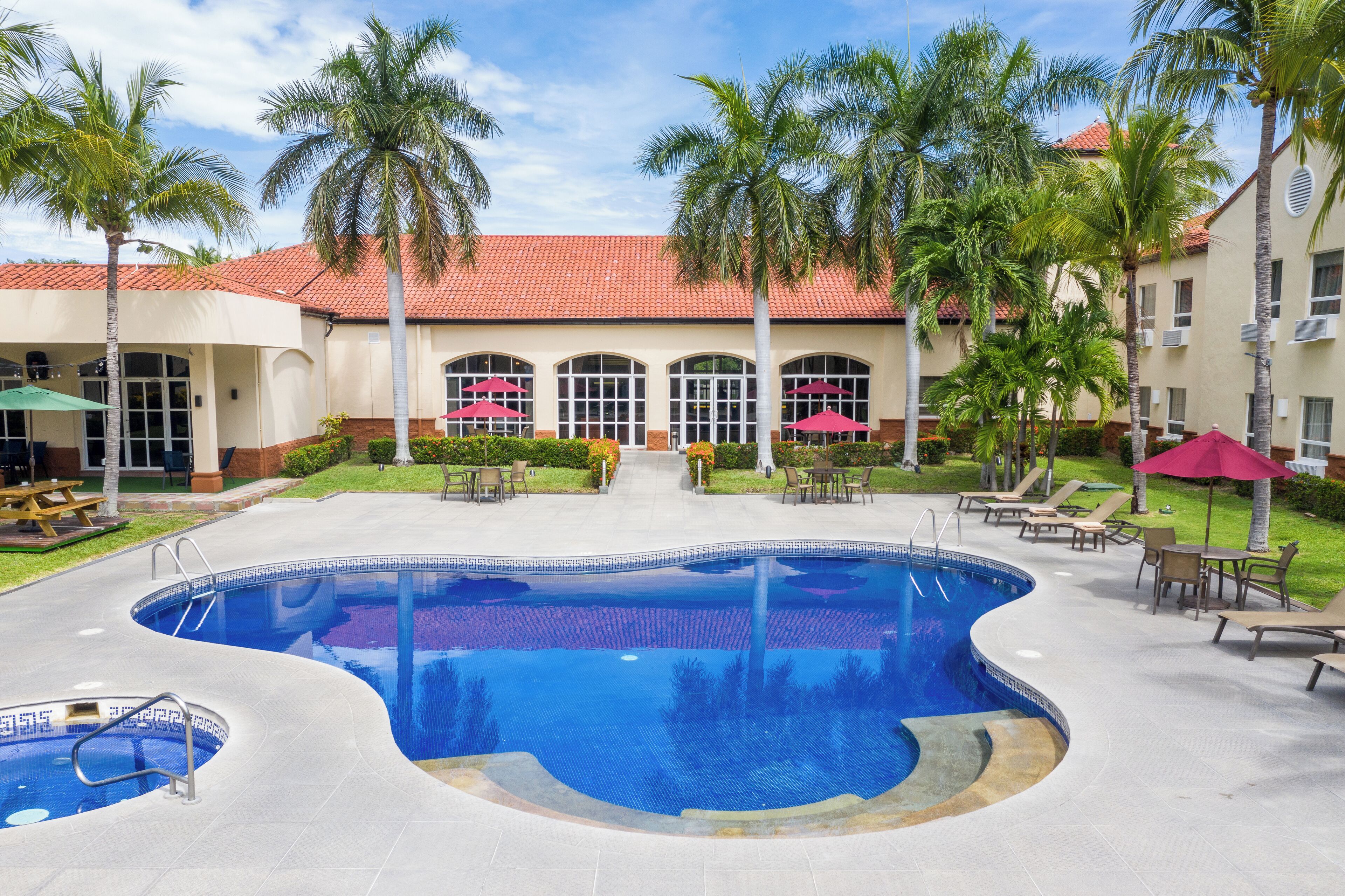 Una piscina al aire libre, sombrillas, sillones reclinables de piscina