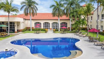 Una piscina al aire libre, sombrillas, sillones reclinables de piscina