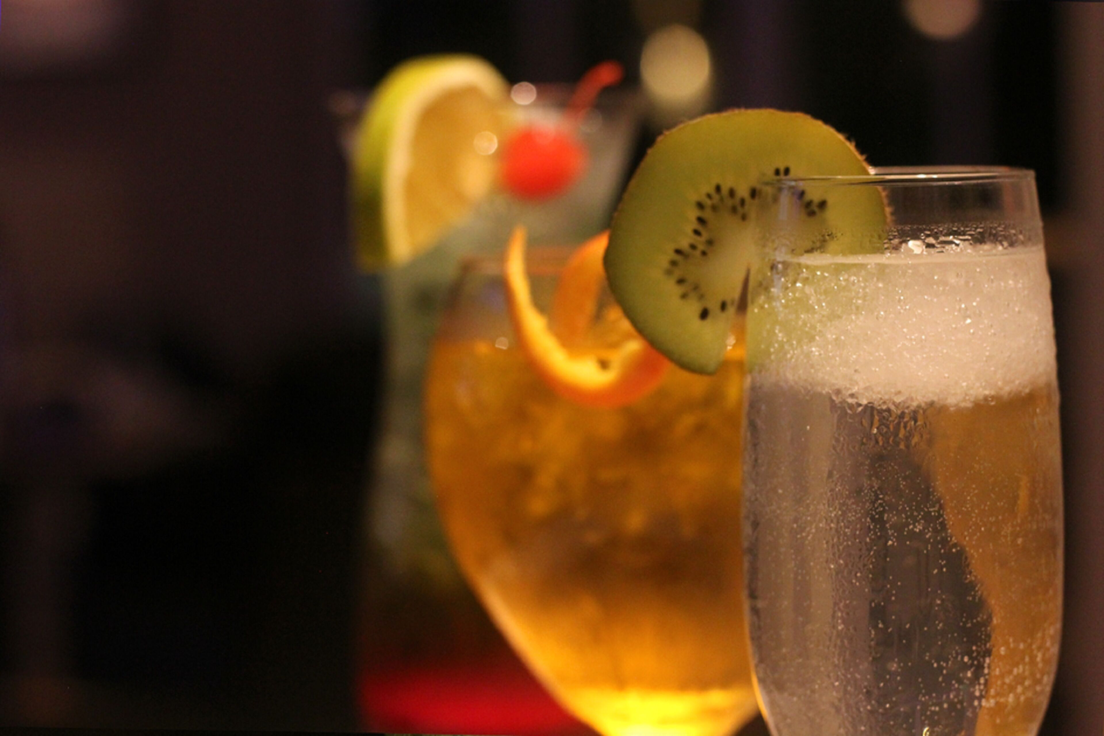 Un verre contenant une boisson claire, agrémenté d’une tranche de kiwi et d’une tranche d’orange.