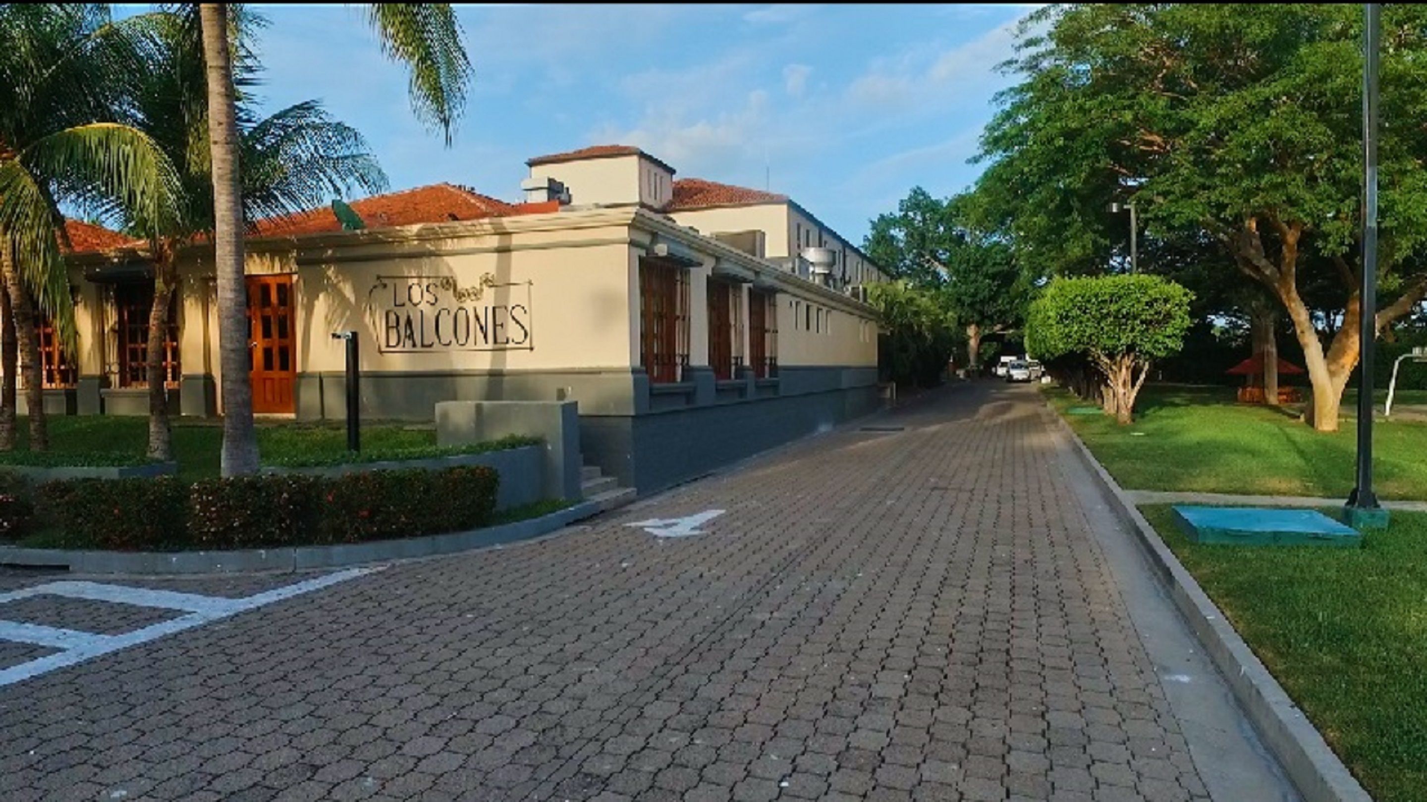 Un edificio con un letrero que dice "Los Balcones" y un camino pavimentado que conduce hacia él.