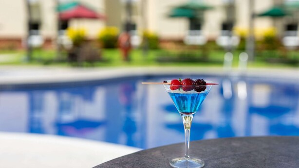 A cocktail with berries in a martini glass by a poolside. - Quality Hotel Real Aeropuerto (San Luis Talpa)