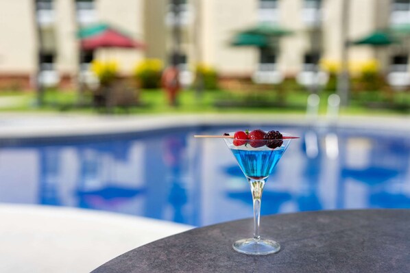 A cocktail with berries in a martini glass by a poolside. - Quality Hotel Real Aeropuerto (San Luis Talpa)