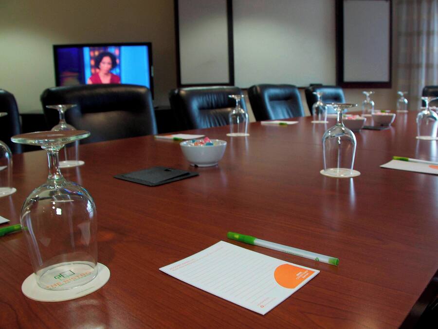 Un salón de conferencias con una mesa larga, sillas, un televisor y un tazón de cereal.