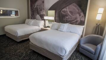 Een hotelkamer met twee bedden, een bureau, een stoel, een lamp en een groot wanddecor.