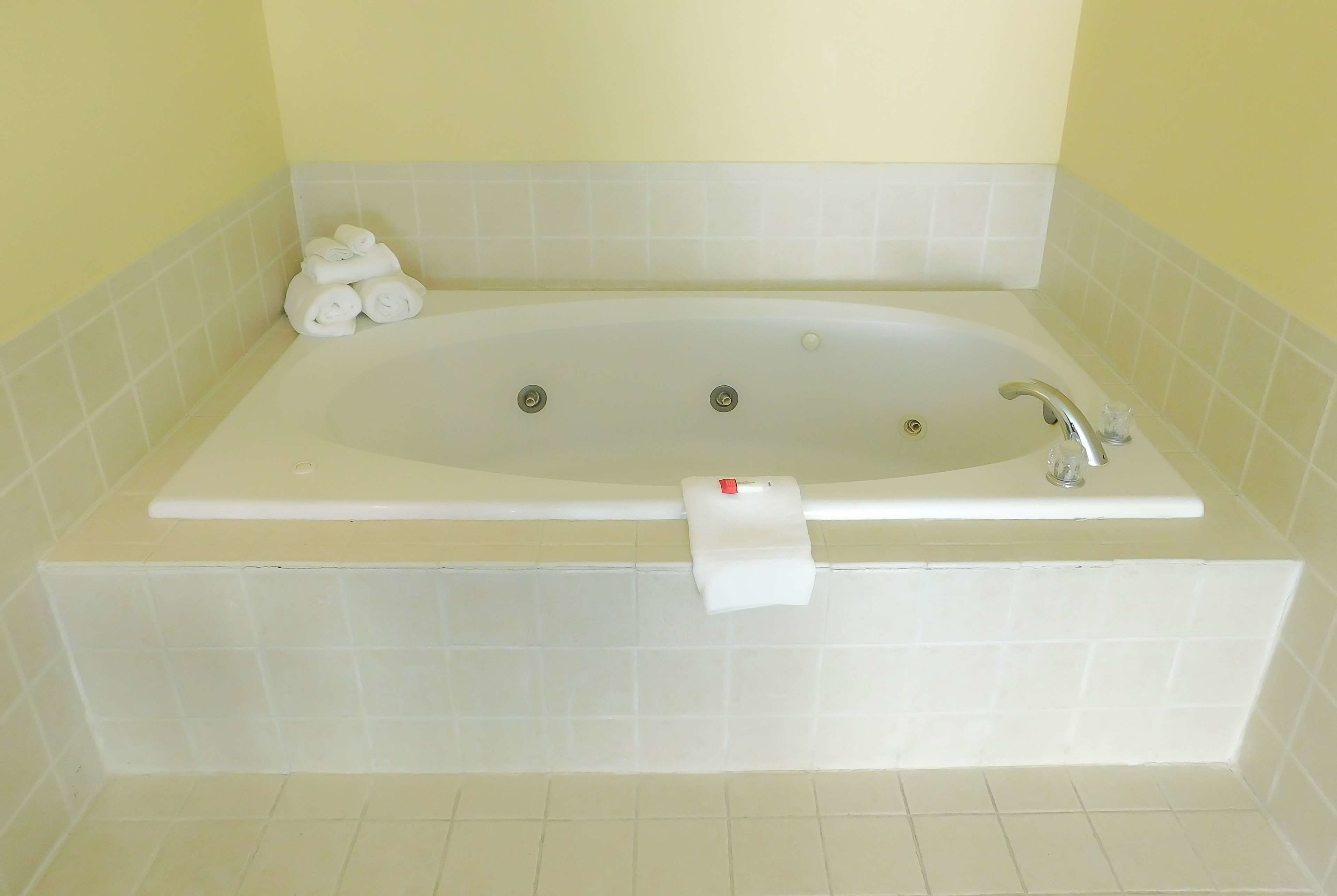A bathroom with a large bathtub, a towel rack, and a toilet paper holder.