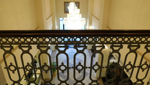 Una amplia escalera con un candelabro en la parte superior, que conduce a un espacio interior bien iluminado.
