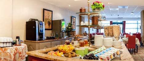 A breakfast buffet with a variety of fruits, beverages, and dairy products.