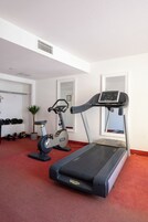 Un gimnasio en casa con cinta de correr, bicicleta estática y varios pesas.