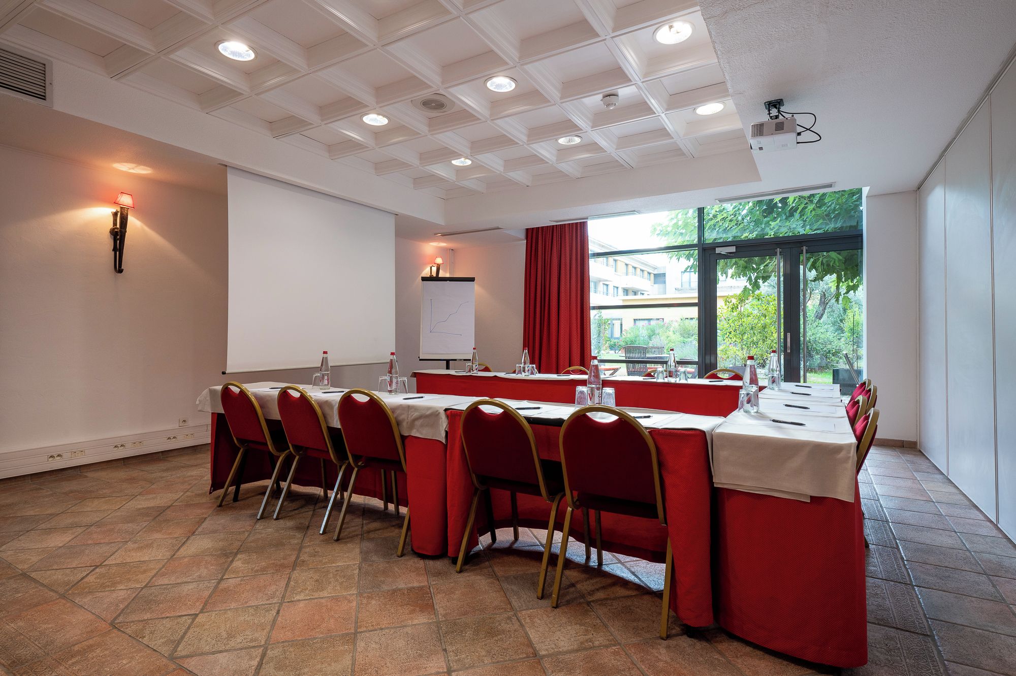 A conference room with a long table, red chairs, a whiteboard, and a projector.