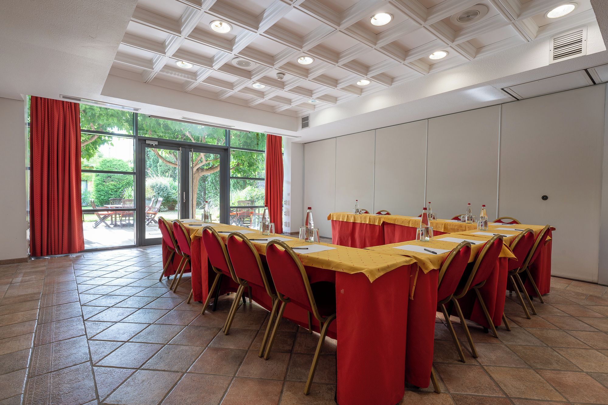 Un salón de conferencias con una larga mesa, sillas rojas y un mantel amarillo.