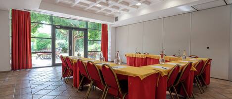 Un salón de conferencias con una larga mesa, sillas rojas y un mantel amarillo.