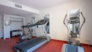 A fitness room with a treadmill, elliptical, and weights.