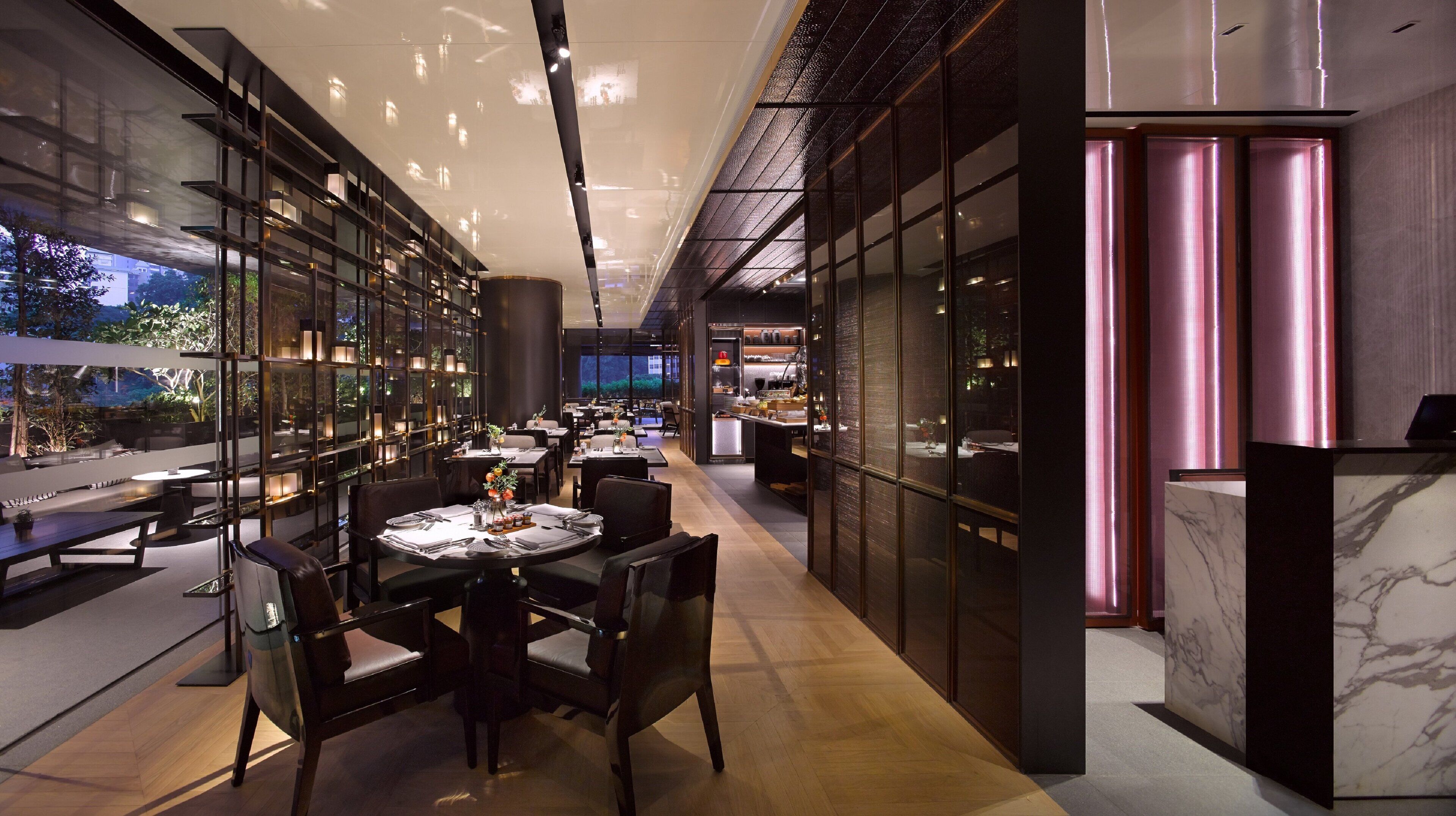 Un restaurant moderne doté d’une grande salle à manger, de cloisons en verre et d’une cuisine visible à travers ces cloisons.