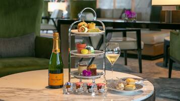 Un expositor de tres niveles con diversos pasteles y una botella de Veuve Clicquot Brut sobre una mesa redonda.