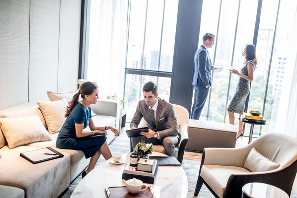 Une chambre d’hôtel moderne dotée d’une grande fenêtre, d’un canapé, d’une table basse avec une théière et d’un ordinateur portable.
