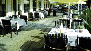 An outdoor dining area with tables and chairs, large umbrellas, and potted plants. - Fletcher Family Hotel Paterswolde (Paterswolde)