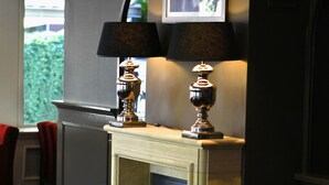 A room with a fireplace, two lamps, and a framed picture on the wall. - Fletcher Family Hotel Paterswolde (Paterswolde)