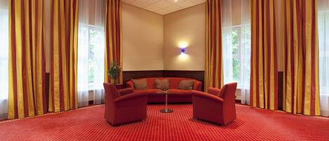 A room with a red carpet, a sofa, and curtains.
