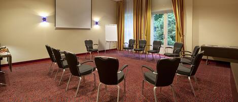 A conference room with a red carpet, black chairs, a whiteboard, and a projector screen.
