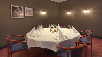 A conference room with a round table set for six, equipped with chairs, tablecloth, and tableware.