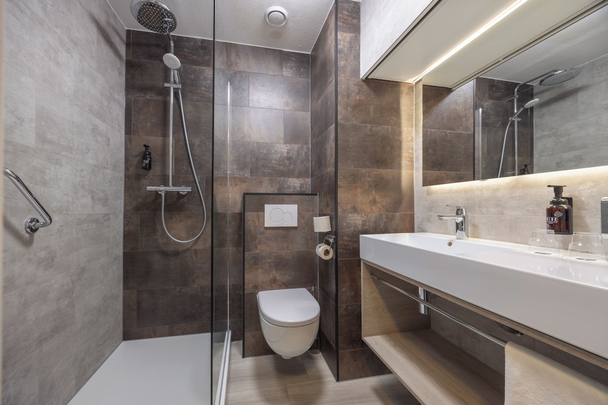 A modern bathroom with a glass-enclosed shower, a toilet, and a vanity with a mirror.