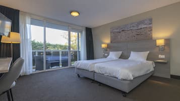 Hotelkamer met een groot bed, bureau, stoel, balkon met uitzicht en een kunstwerk aan de muur.