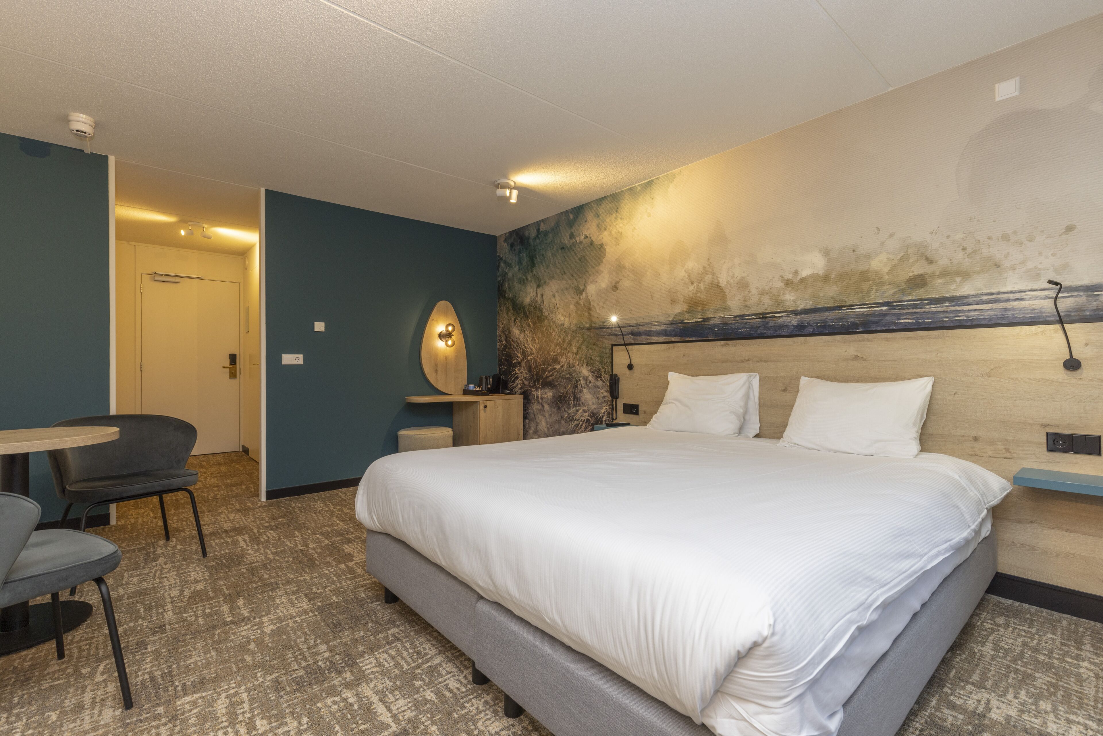 Ein Hotelzimmer mit einem großen Bett, einem Schreibtisch und einem Stuhl.