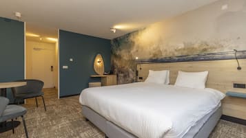 Ein Hotelzimmer mit einem großen Bett, einem Schreibtisch und einem Stuhl.