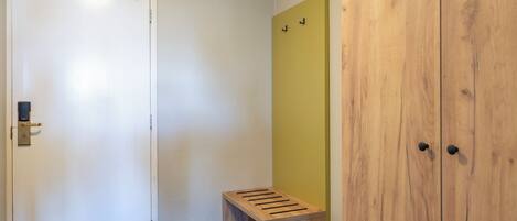 A hallway with a white door, a wooden bench, and a yellow wall.