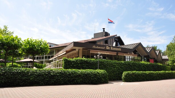 A restaurant with a modern architectural design, featuring a prominent entrance and a flag on top. - Fletcher Hotel-Restaurant Jan van Scorel (Schoorl)