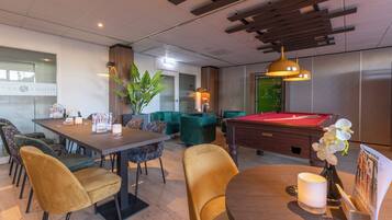 A modern lounge area with a pool table, comfortable seating, and a billiards table.